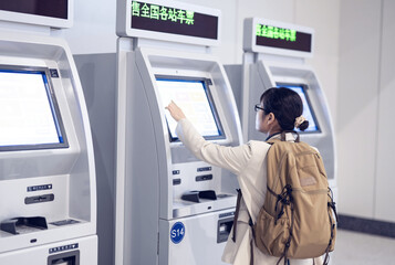 Backpacker travelers buying tickets from the automatic ticket machine at the train station