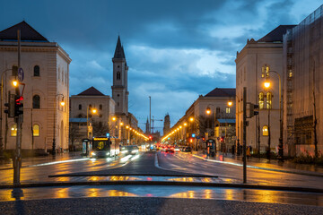 View from the Siegestor onto Ludwigstrasse with its famous buildings in Munich, Bavaria, Germany at blue hour. Motion blur of car headlights due to long exposure. - obrazy, fototapety, plakaty