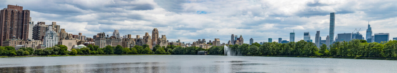 The New York skyline as seen from the lake in Central Park which is a public urban park located in...