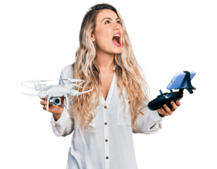 Young blonde woman holding television remote control angry and mad screaming frustrated and furious, shouting with anger looking up.