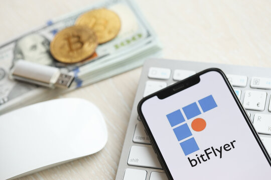 KYIV, UKRAINE - MARCH 15, 2024 Btflyer logo on iPhone display screen on white keyboard with money and bitcoins. Cryptocurrency exchange portal