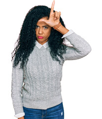 Middle age african american woman wearing casual clothes making fun of people with fingers on forehead doing loser gesture mocking and insulting.