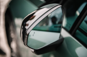 Blind zone monitoring sensor on the side left mirror of a new modern electric sedan car. View of...