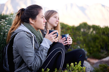 Hiking, women and friends drinking coffee outdoor, thinking or relax in environment. Trekking, nature and girls with tea cup on adventure, travel and serious on vacation together for journey by bush