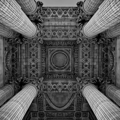 Low angle of an ornate ceiling with columns of an old building in grayscale