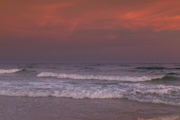 a surfer riding waves under a sunset sky at the beach