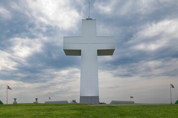 Bald Knob Cross of Peace, situated in a lush green meadow with flags fluttering in the background