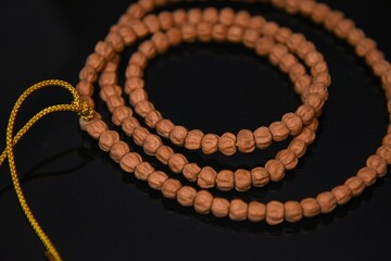 Fototapeta premium Overhead closeup of bodhi prayer beads with a golden string on a black table