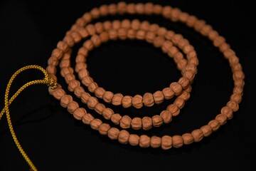 Overhead view of bodhi prayer beads with a golden string on a black table