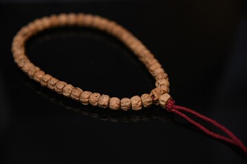 Overhead view of bodhi prayer beads with a red string on a black table