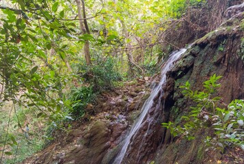 Breathtaking view of a scenic hiking trail with a waterfall cascading over the edge of a rocky cliff
