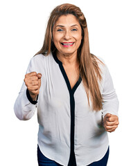Middle age latin woman wearing business shirt very happy and excited doing winner gesture with arms raised, smiling and screaming for success. celebration concept.