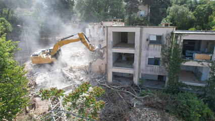 Excavator arm demolishing an old building, Aerial view