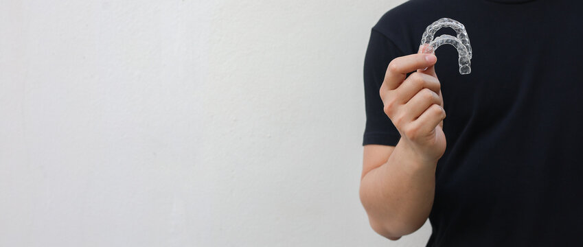close up young asian man  hand holding dental aligner retainer (invisible) at dental clinic for beautiful teeth treatment course concept