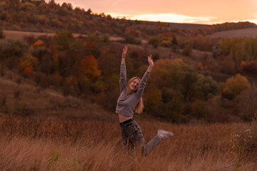 Fototapeta premium Young attractive blonde woman standing on the hill at sunset 