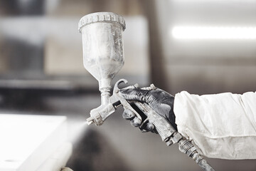 Close-up of industrial worker using paint gun or spray gun for applying paint, airless spraying.