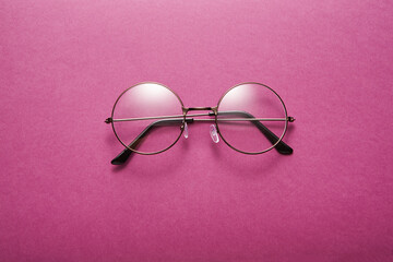 Glasses in round thin metal frame isolated on violet surface.