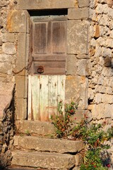 Vertical shot of an old stone wall with a weathered wooden door