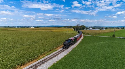 A Drone Frontal View of a Restored Steam Passenger Train, Traveling Thru Green Corn Fields