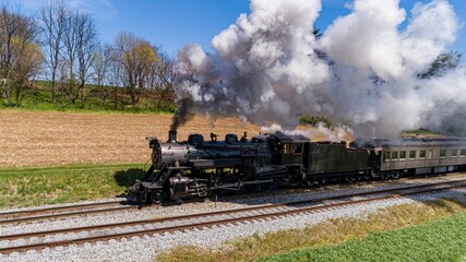 Obraz premium Antique Steam Passenger Train Traveling Thru Farmlands, With Crops Planted, Blowing Smoke