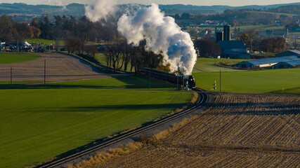 Aerial View at Sunrise of a Steam Passenger Train Approaching Blowing A Lot of Smoke