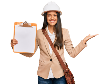 Beautiful hispanic woman architect showing black space on clipboard celebrating victory with happy smile and winner expression with raised hands