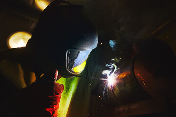 Man in protective mask welding metal construction.