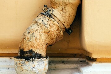 a pipe on the side of an old building showing rust