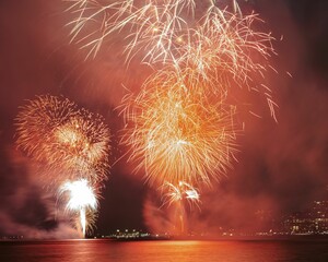 Vibrant display of fireworks bursting in the night sky above a tranquil body of water