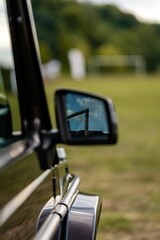 Side view mirror of a truck parked in a grassy area near a soccer field