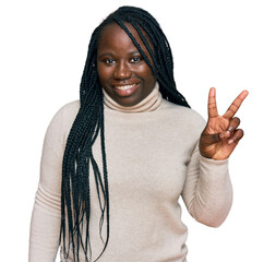 Young black woman with braids wearing casual winter sweater smiling with happy face winking at the camera doing victory sign. number two.