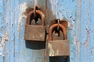 Rustic padlock is securely fastened onto a wooden door, with distressed and deteriorated condition