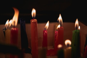 Close-up shot of multiple lit candles placed in a metal pan on a counter