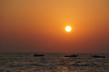 small boats are in the water at sunset over the ocean