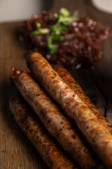 Grilled sausages with mustard and herbs on a wooden board