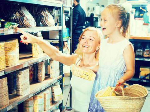 Mother with daughter buy corn cakes in store
