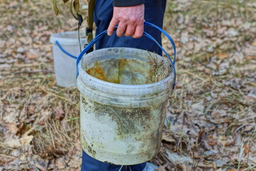 one  dirty round old discarded empty broken white plastic bucket in the hand of a worker during the day on the street