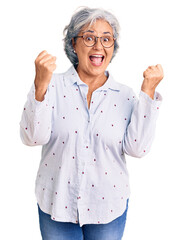 Senior woman with gray hair wearing casual business clothes and glasses screaming proud, celebrating victory and success very excited with raised arms