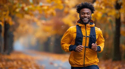 Fotobehang Happy man jogging in autumn park with colorful leaves, wearing a yellow jacket and backpack. © amixstudio