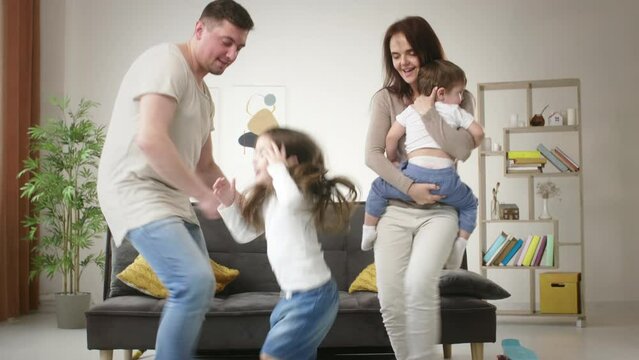 Happy family with little kids dancing together in living room