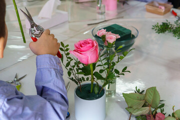 a little boy at a master class on making bouquets of flowers in boxes. No face, just hands and a bouquet.
