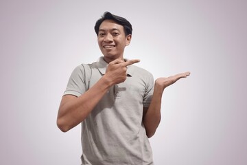 Handsome happy Asian man showing something with his palms in front, man holding something with both hands. Indonesian man holding something in his palm to insert an advertisement. Copy space image.