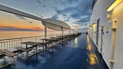 Stunning view of a ship's deck with multiple tables and chairs at sunset