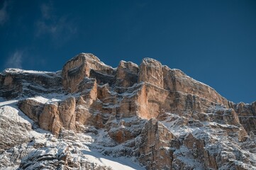 skiiers are going up the snowy slopes next to some large, rocky peaks