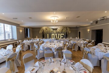 Empty wedding reception area set up with tables, ready for guests to arrive