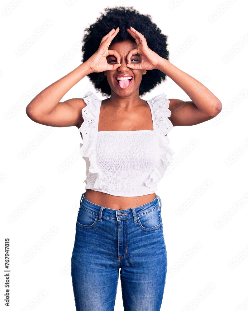 Wall mural Young african american woman wearing casual clothes doing ok gesture like binoculars sticking tongue out, eyes looking through fingers. crazy expression.