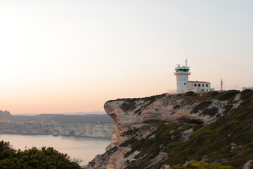 A scenery view of a mini picturesque Lighthouse on a mountain top during sunset