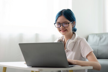 Happy young woman looking at laptop making note, girl student talking by video conference call,...