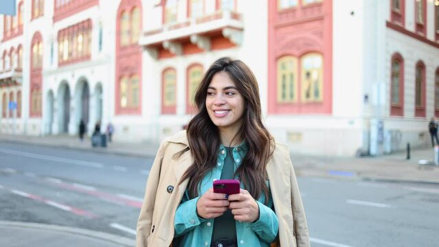Happy Latin woman surfing the net in the city