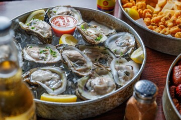Closeup of a Cajun meal , Fresh oysters, and beer on the wooden table